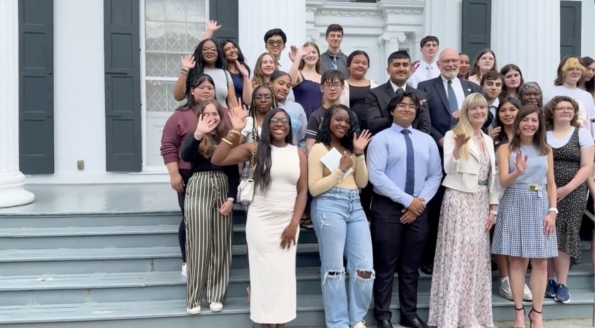 Group of students standing on steps, waving