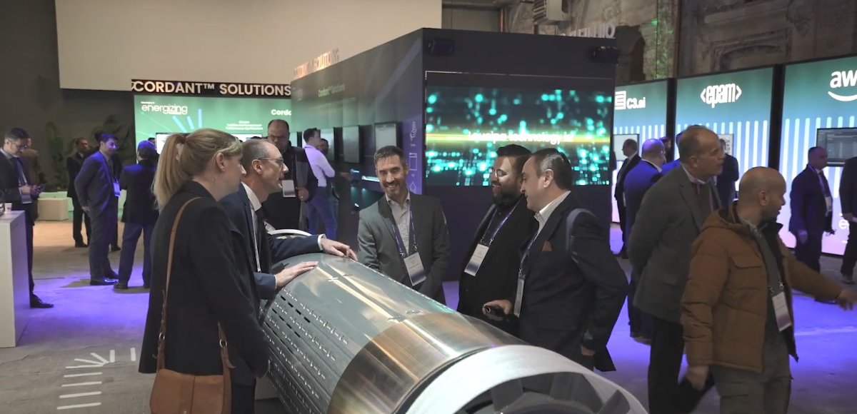 People talking over a large metal cylinder at a convention.