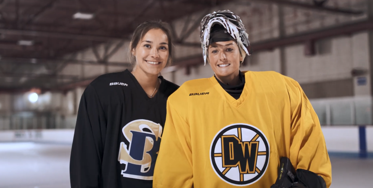 Two Alumni in hockey uniforms posed together on an ice rink.