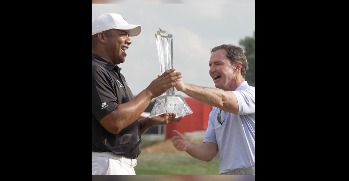 Two people celebrating, one holding a trophy.