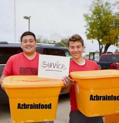 Two men holding up orange containers with black text