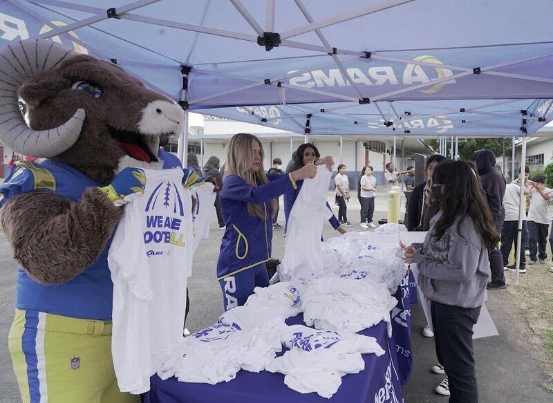 Los Angeles Rams' mascot and others holding t-shirts that read "WE ARE FOOTBALL"