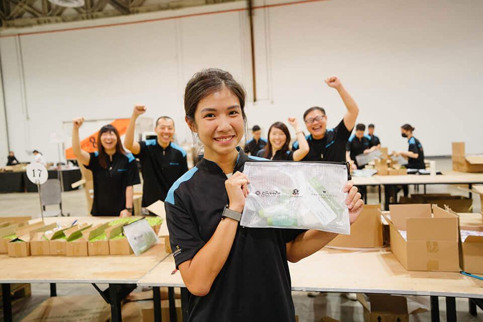 Someone holding up a hygiene kit, with cheering people in the background