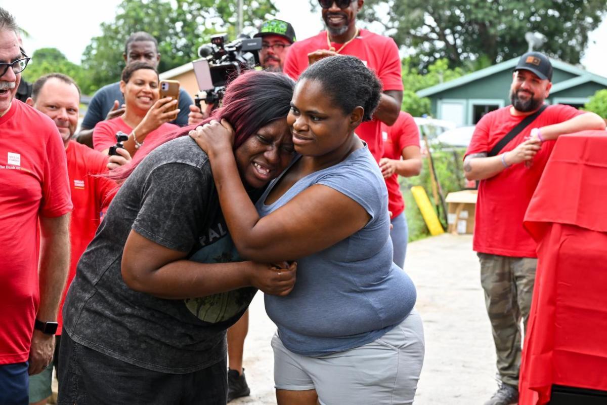 Two women hugging, surrounded by Wells Fargo Volunteers