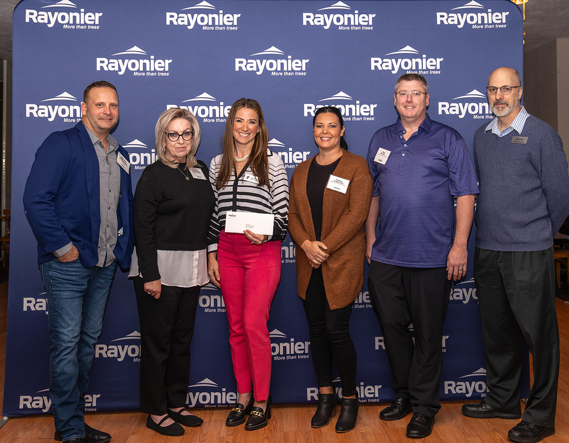 Six people standing together, one holding a check