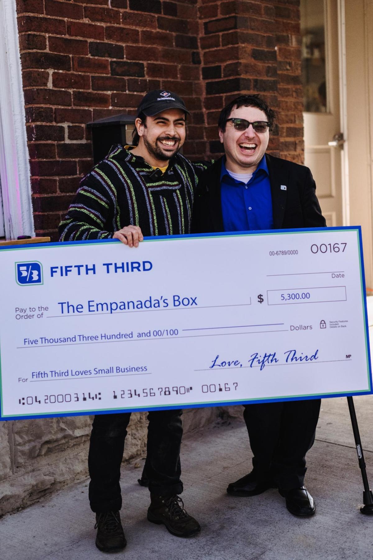 Two smiling people holding an oversized check