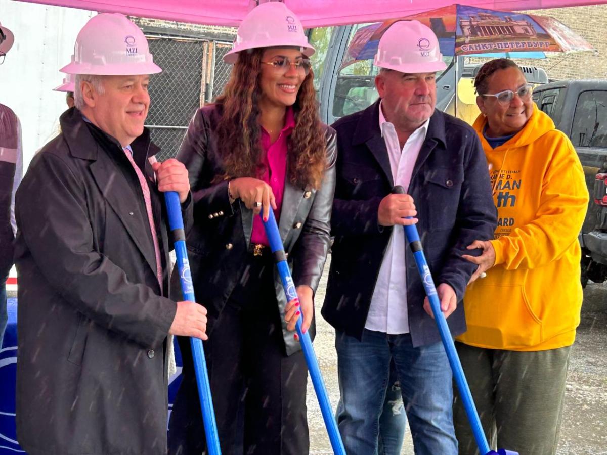 Four people standing together with shovels and hardhats in a breaking ground ceremony