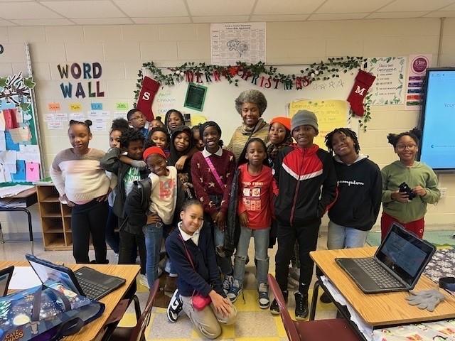 Students and teacher stand in front of classroom