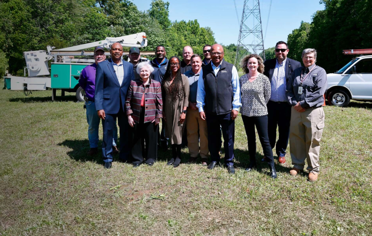 People standing together in a field in front of communication equipment