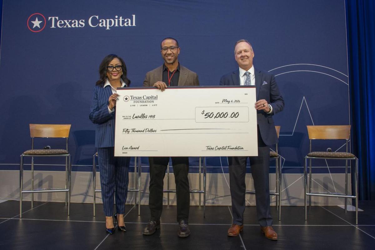 Three people holding a large check