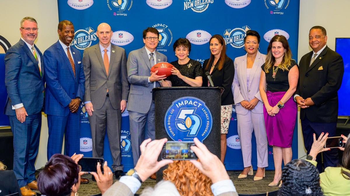 People on a stage behind a podium holding a football