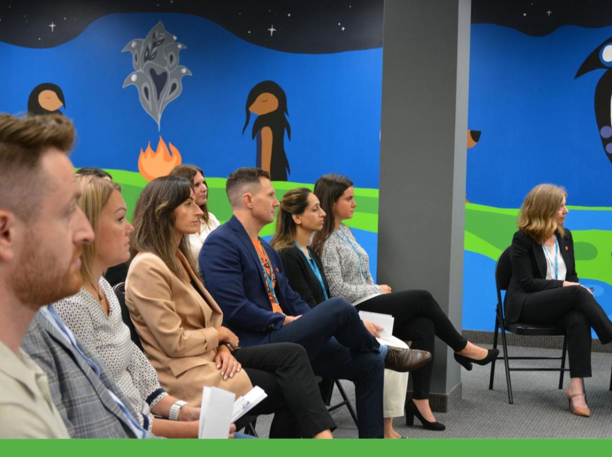 People seated at a presentation, with a large mural in the background