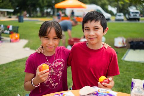 Two children holding fruit and posing