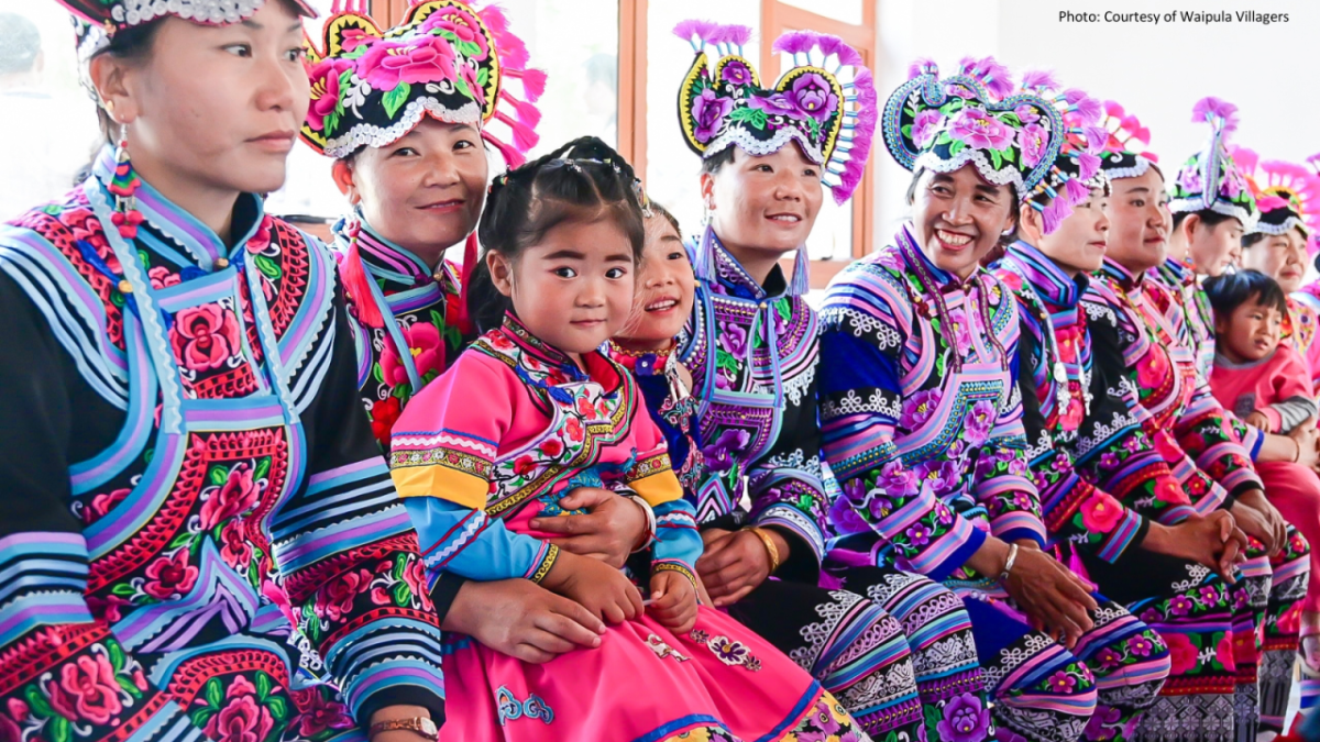 A group seated in a row, each wearing colorful, detailed cultural garments.