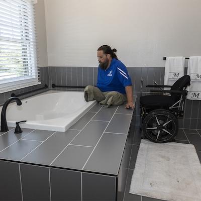 Veteran amputee shown getting into his tub.