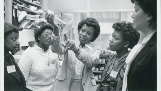 Five people examining a beaker