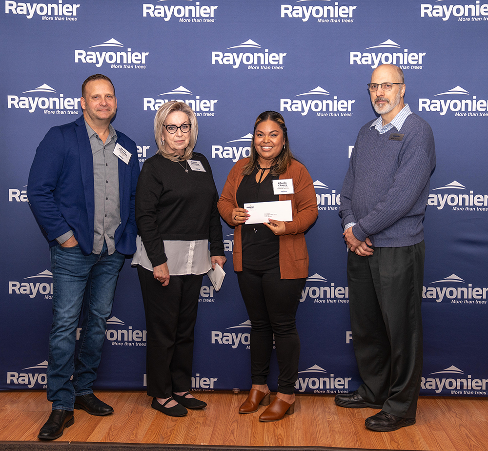 Four people standing together, one holding a check