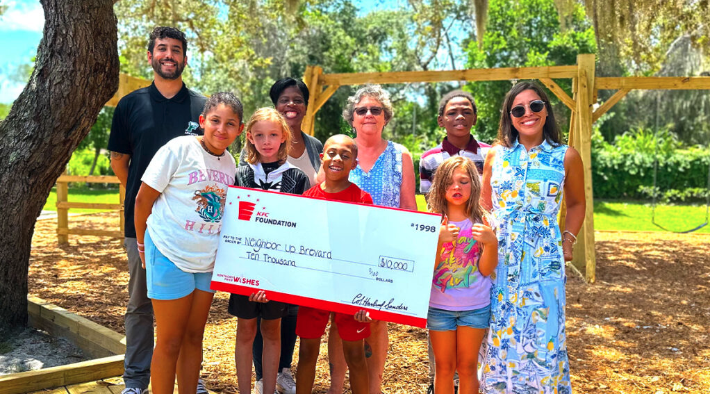 A group of children and adults posing and smiling with an oversized check