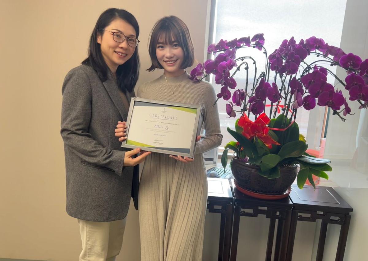 Two people standing together, holding a diploma