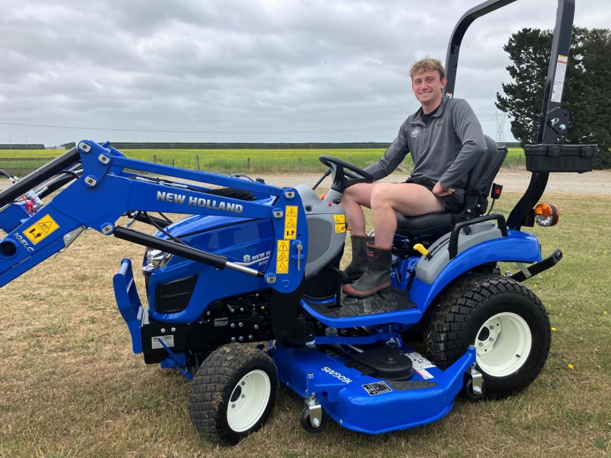 A person sitting on a blue tractor in a field