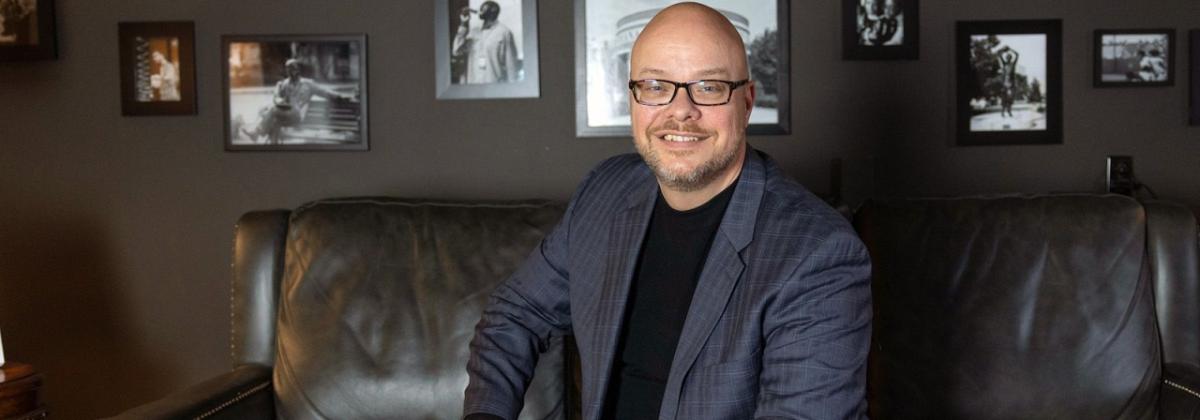 Andy Smith in a gray suit, sitting on a dark sofa