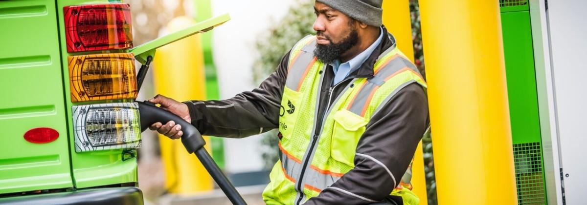 worker in a safety vest plugging in an electric bus