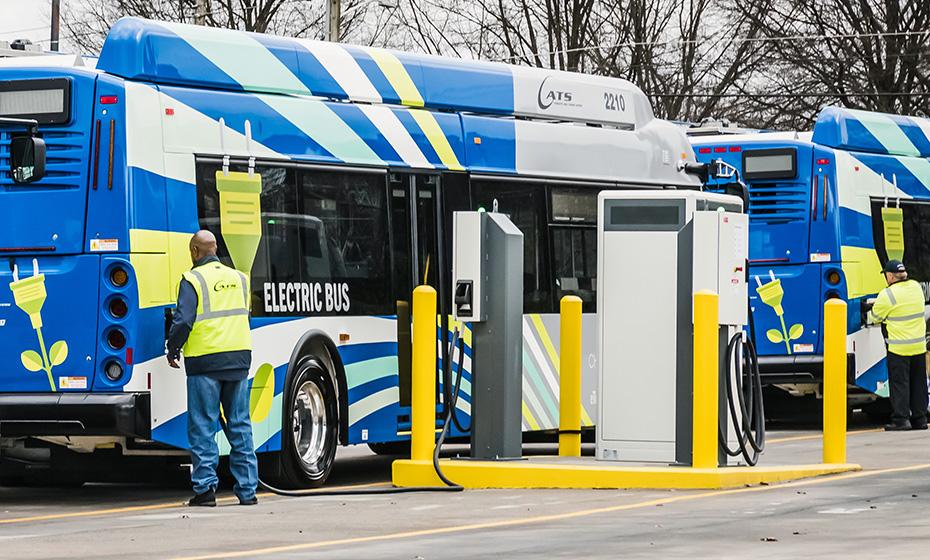 workers in safety gear charging electric buses