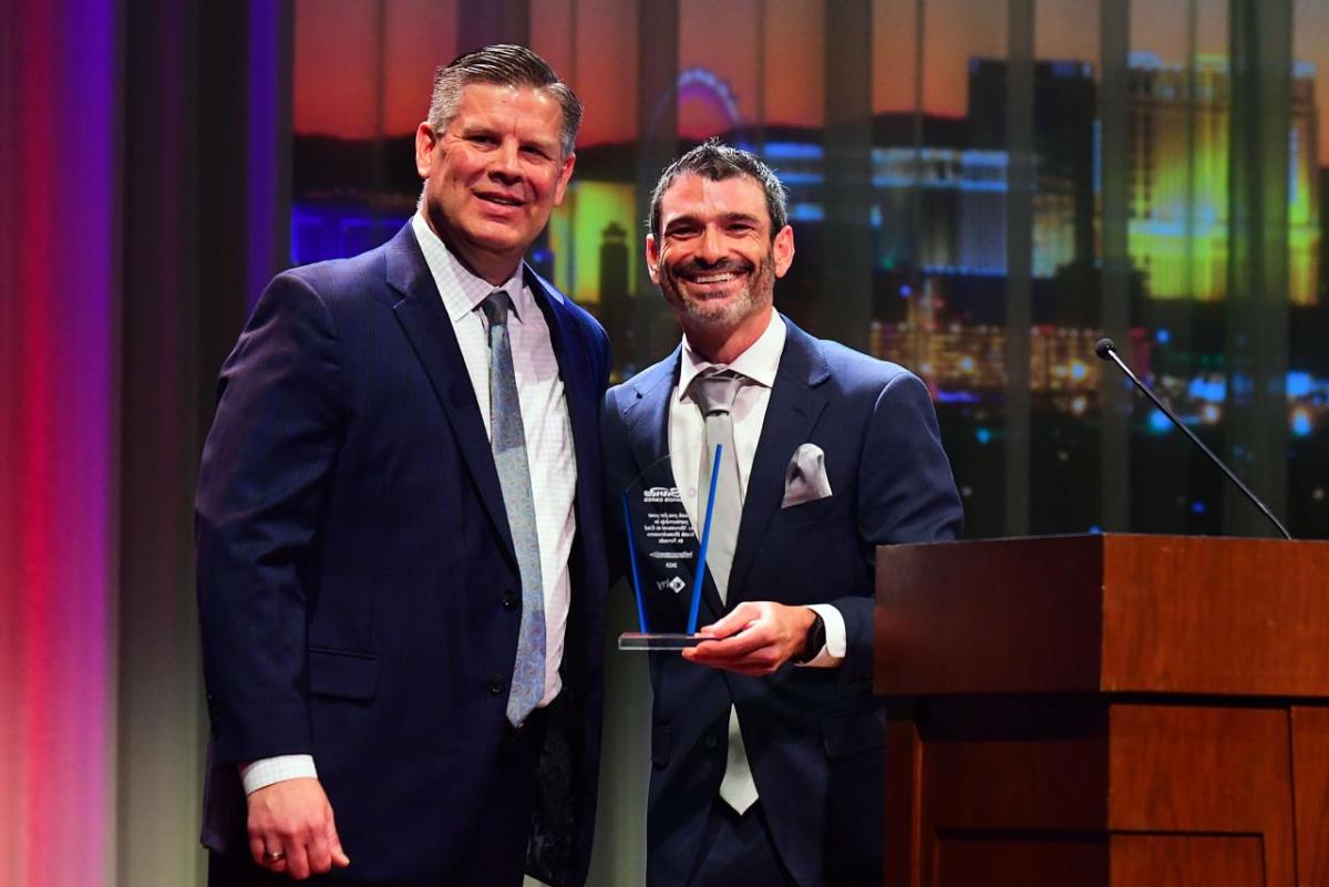 Two people stood together posing for a photo, one person holding an award