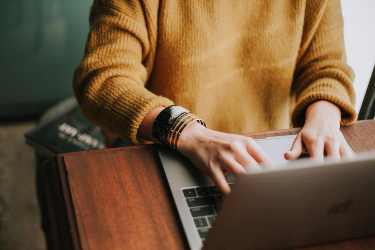 Person seated at a desk typing on a laptop.