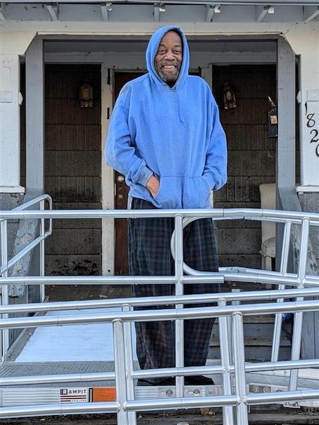 Roy shown in front of his house on the wheelchair ramp.