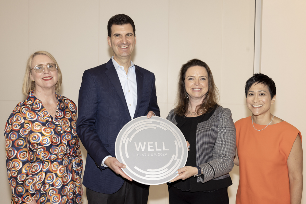 Four people standing together, holding a round award