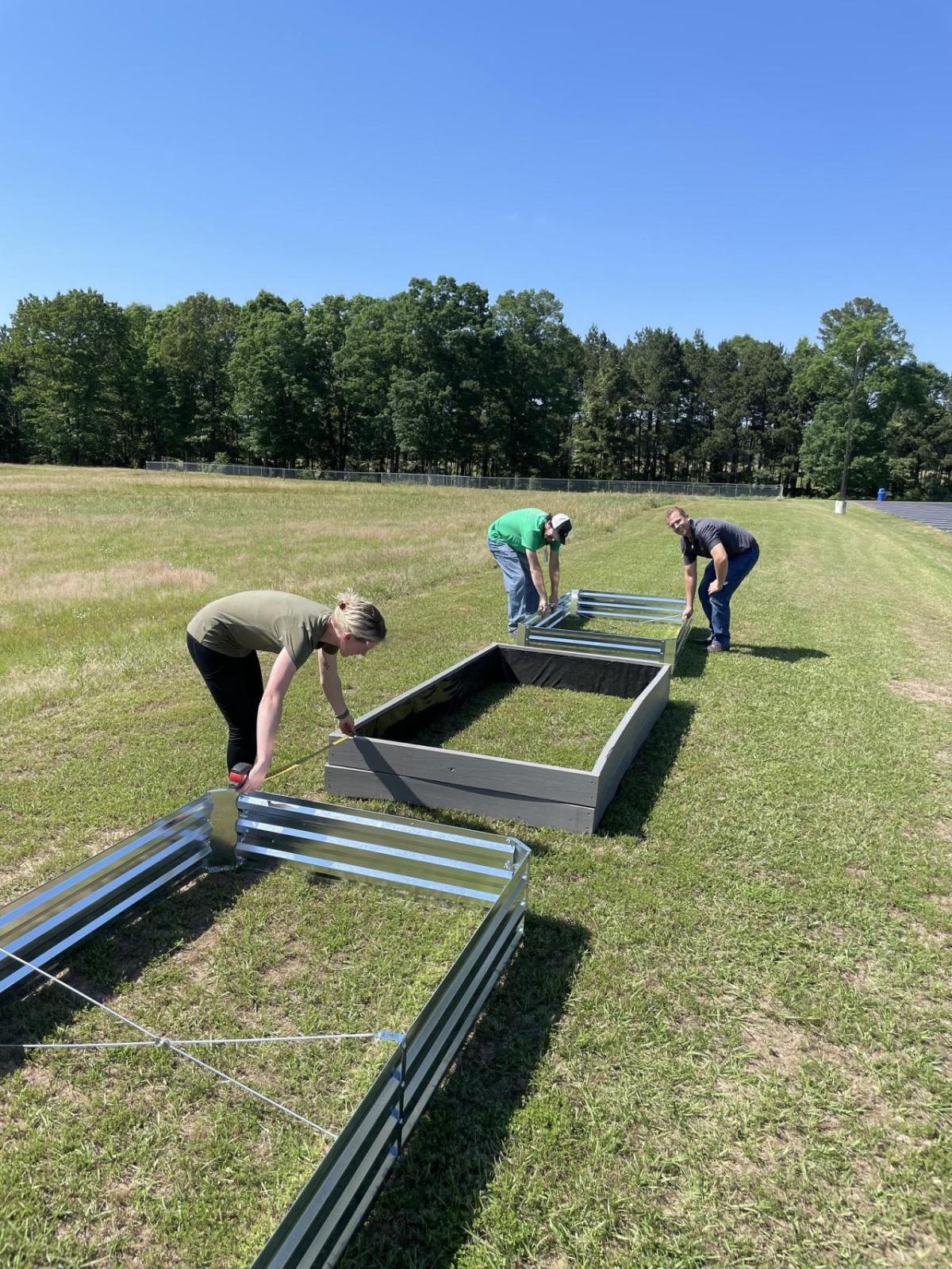 A team of people helping to build raised beds in a field for planting fruit and veg