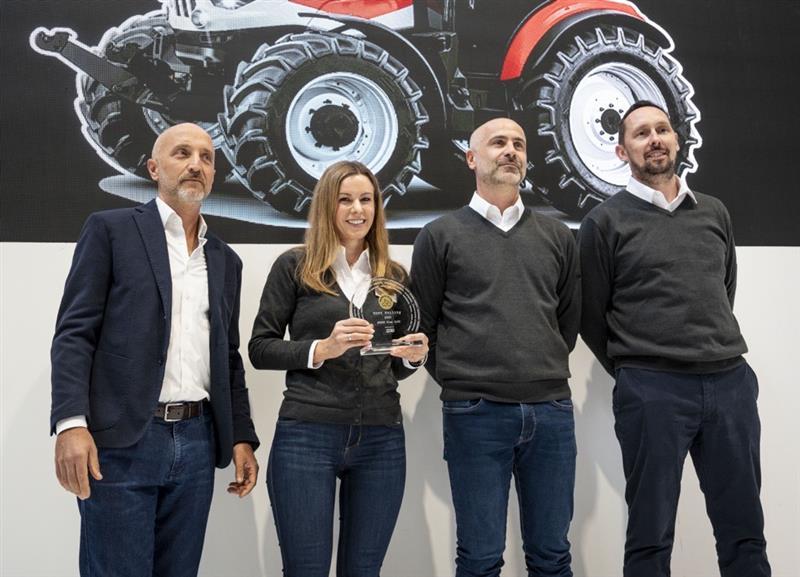 Four people posing together, one holding an award.