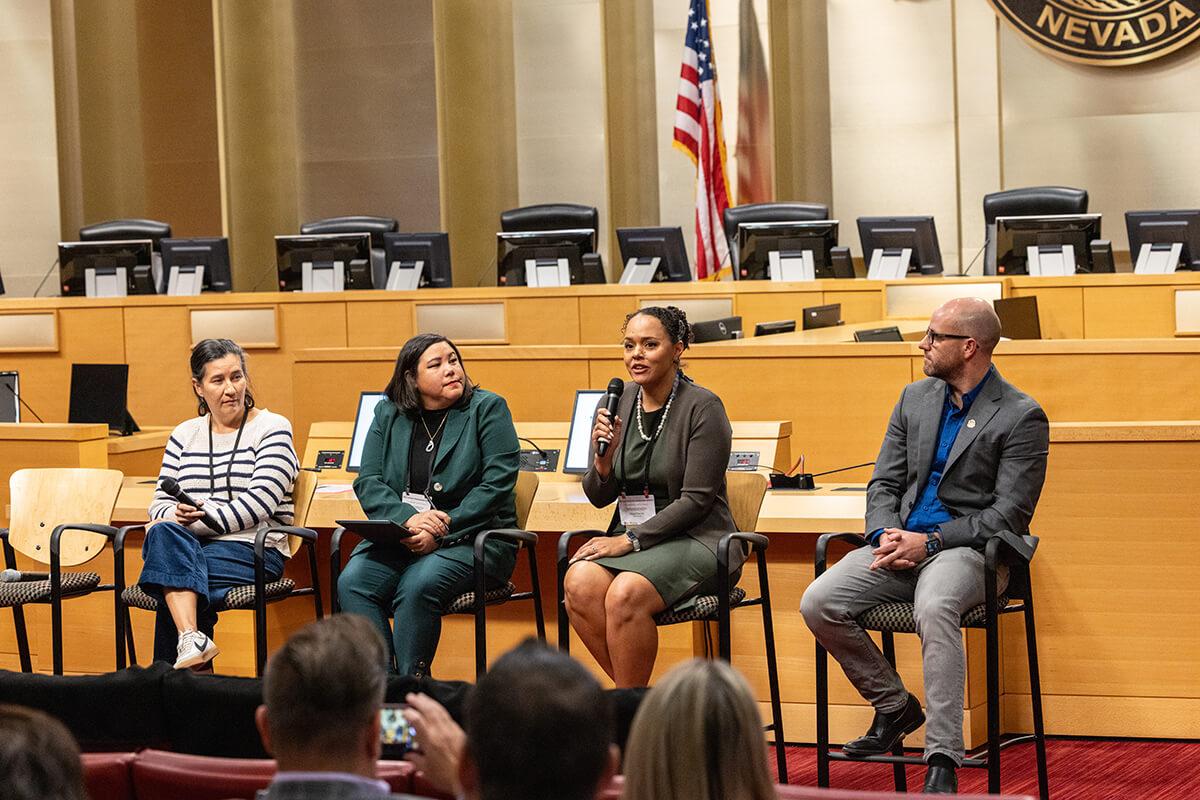 Four people seated, one speaking into a microphone