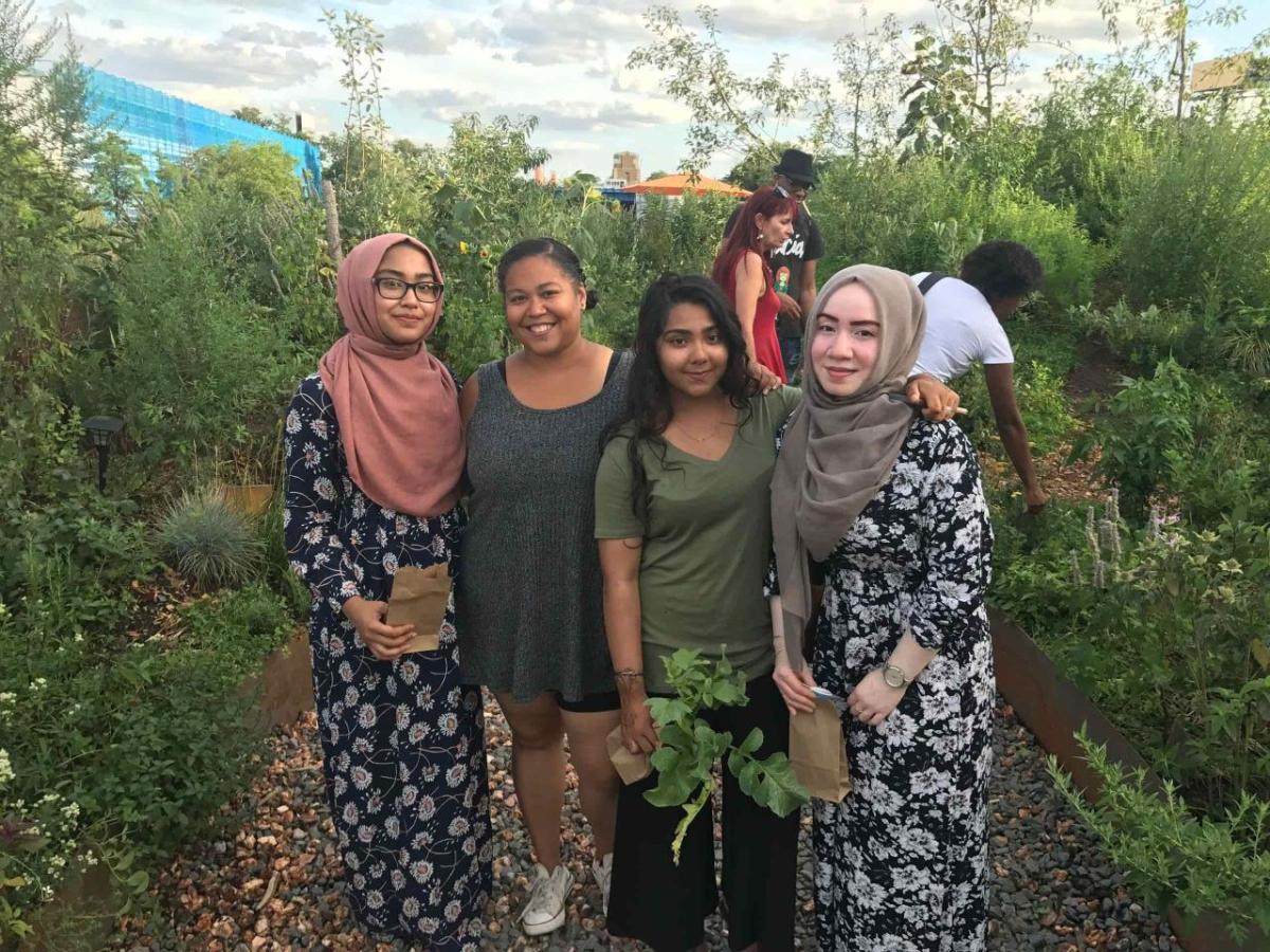 People standing together and smiling with greenery behind them