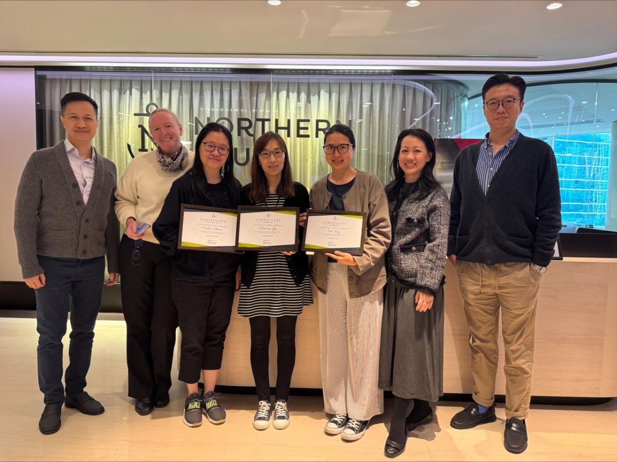 7 people standing in an office together, 3 holding diplomas