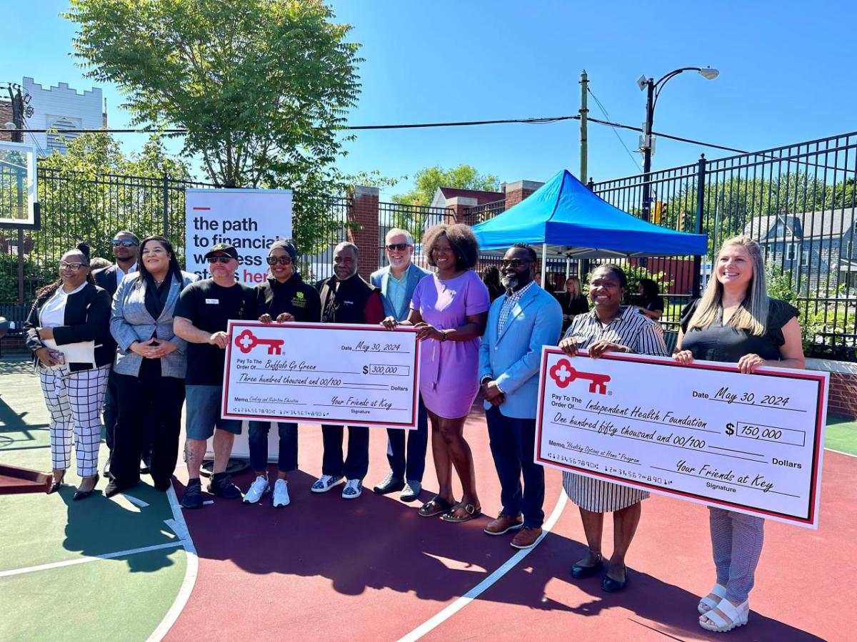 People standing together, holding two oversized checks