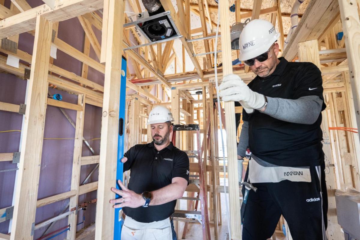 Two people framing a room in a house