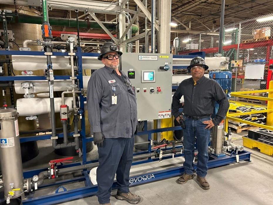 Two workers in hard hats standing by machinery