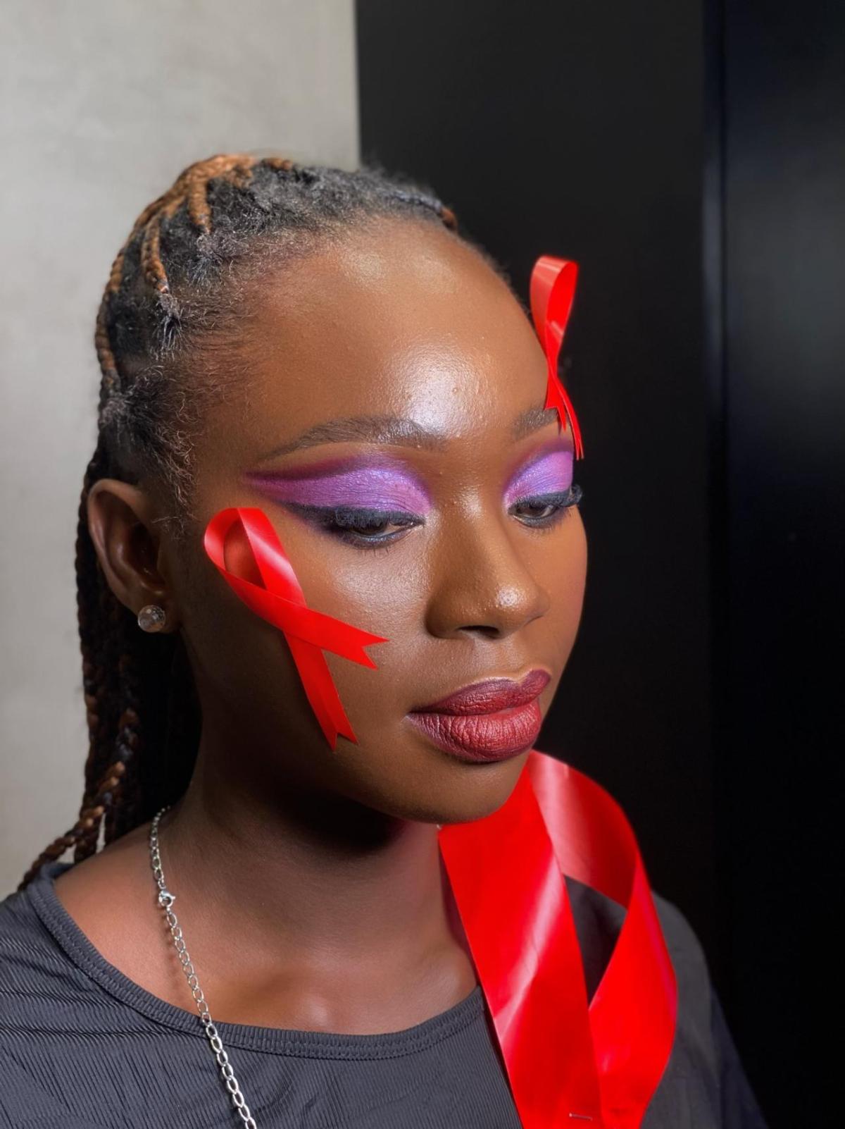 Person with purple eye makeup and red ribbons on their face