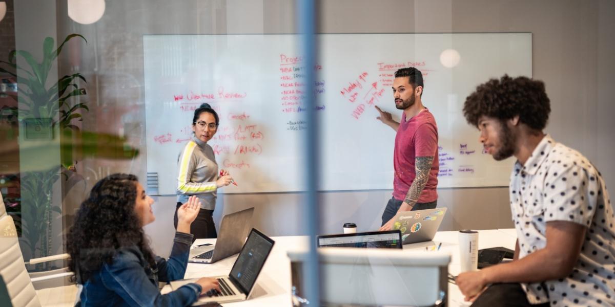 people working together and writing notes on a whiteboard