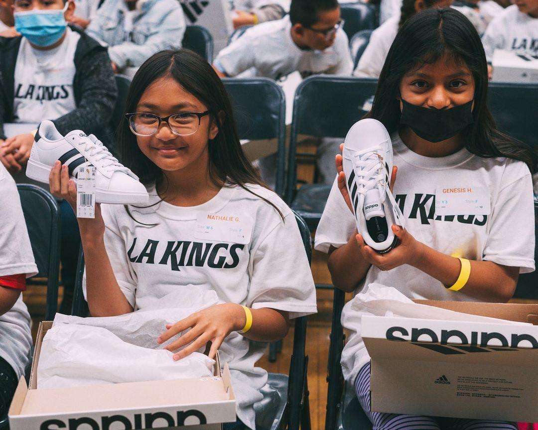 Two students showing off their new sneakers provided by the LA Kings and Shoes That Fit.