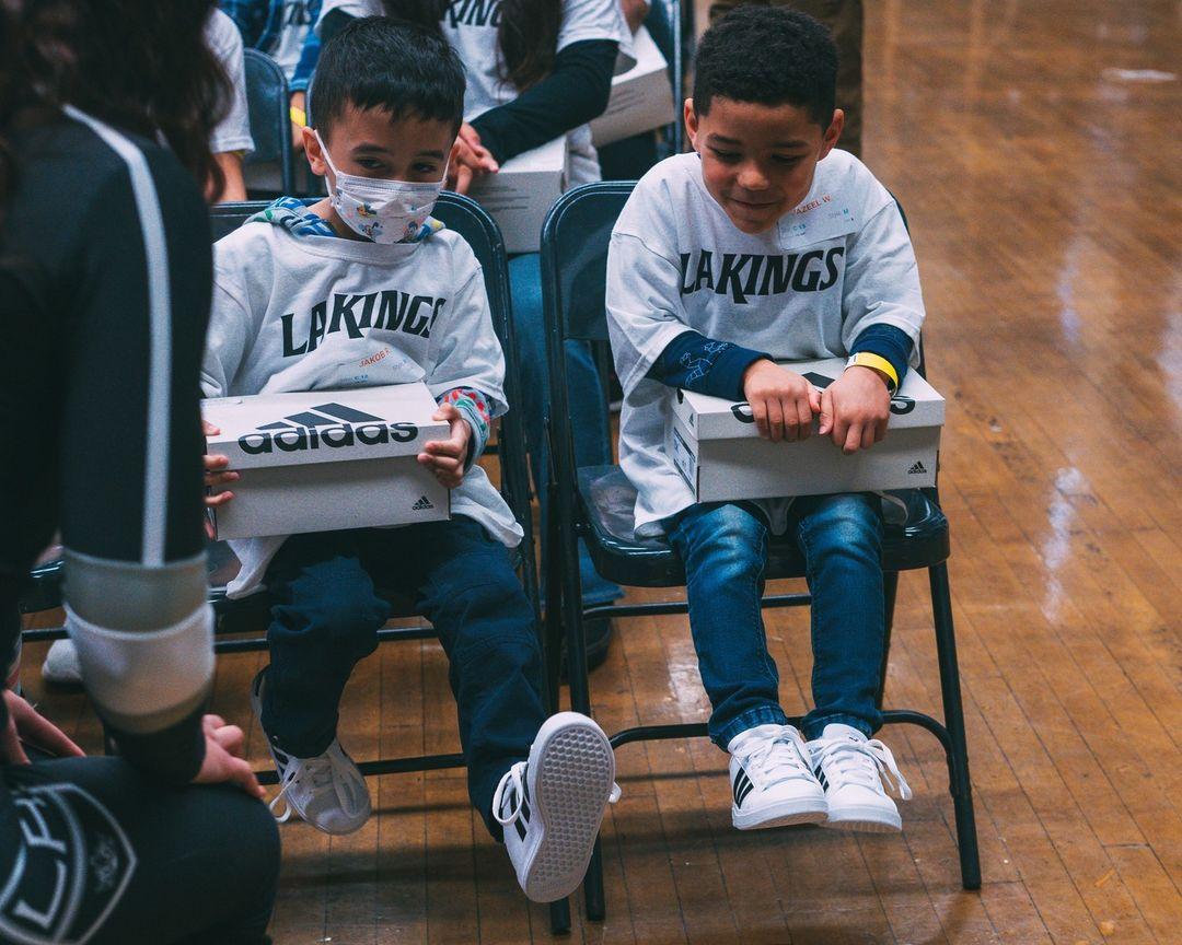 Students from Grant Elementary in Los Angeles, CA smiling as they try on their new shoes.