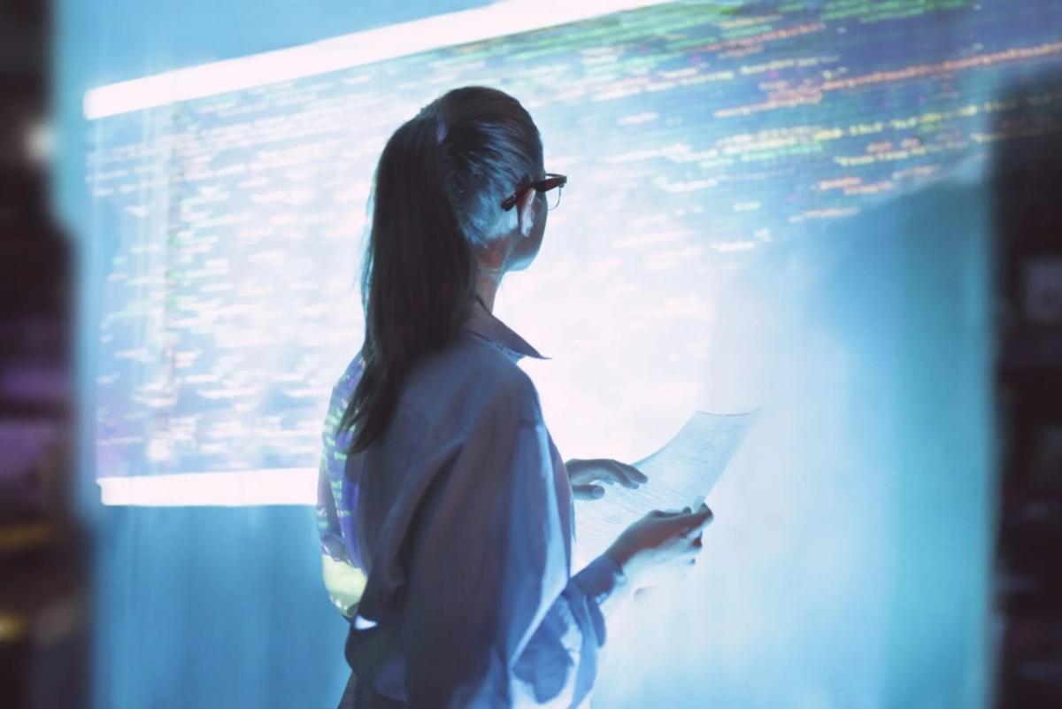 person looking at computer code on a large screen