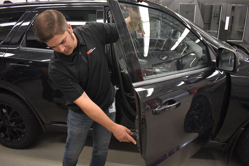 Shop technician inspecting a car door.