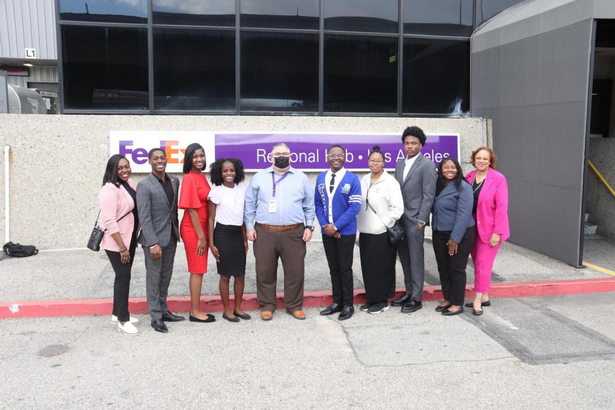 A group of people stood in a line in front of a FedEx banner