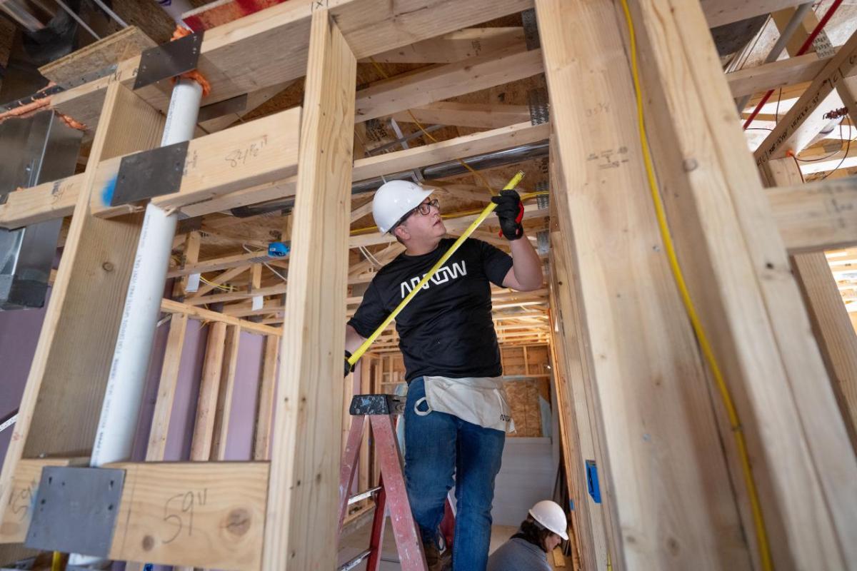 A person measuring part of a frame inside a house