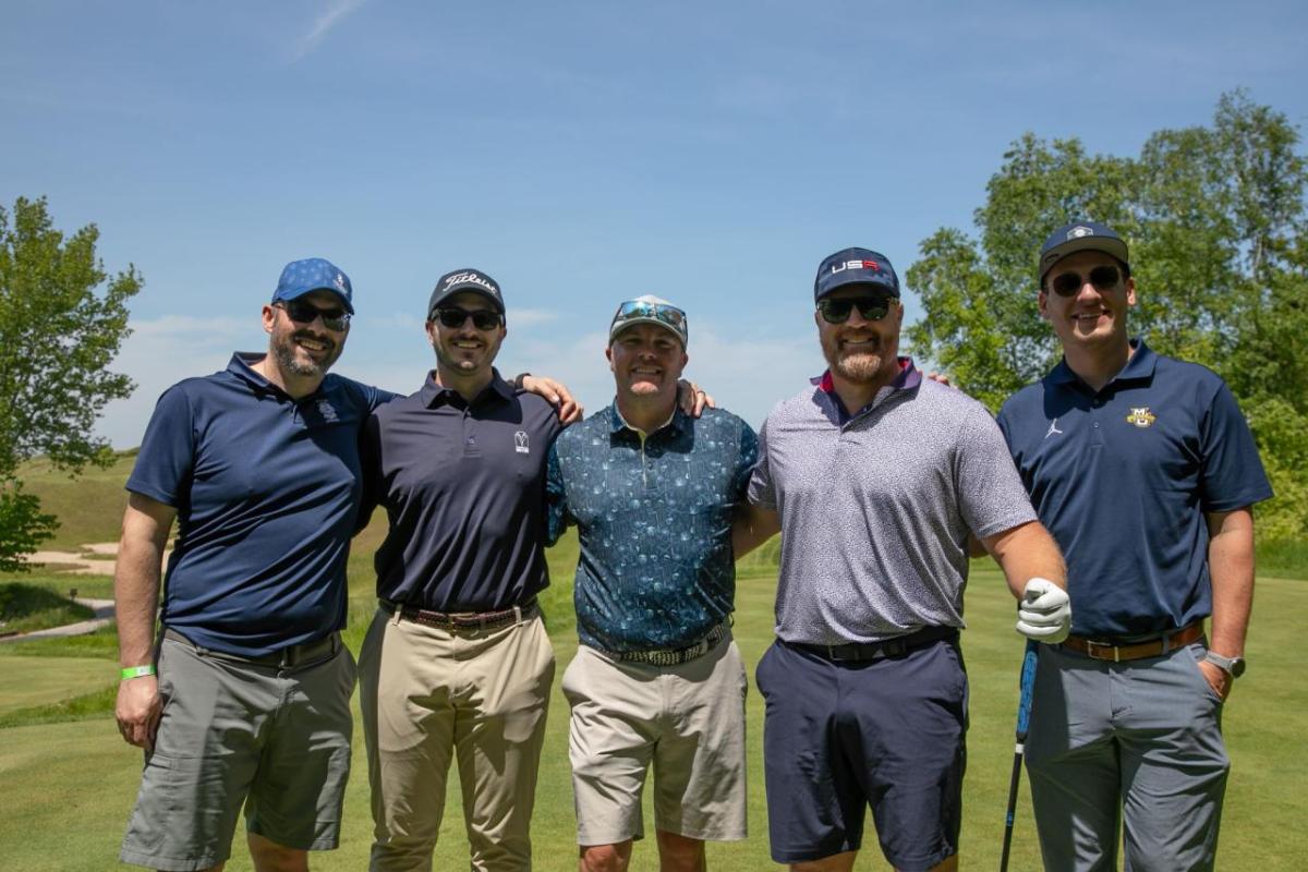 Five people in blue standing together outside