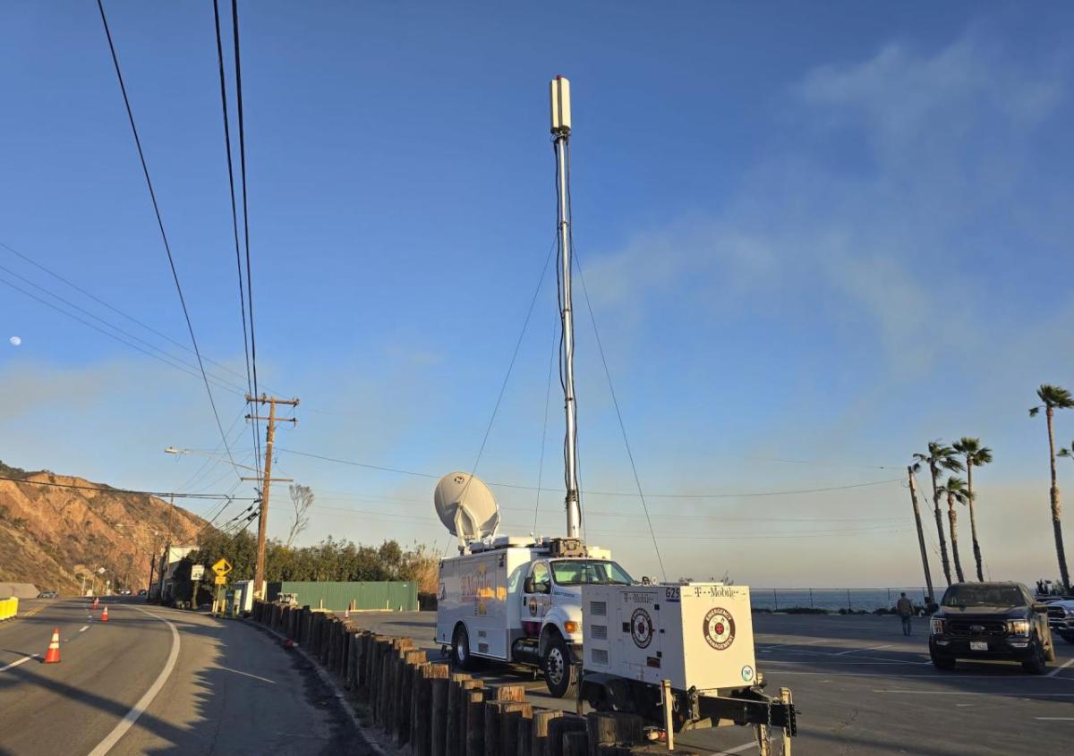 A T-Mobile vehicle on a highway next to a telephone pole and wires