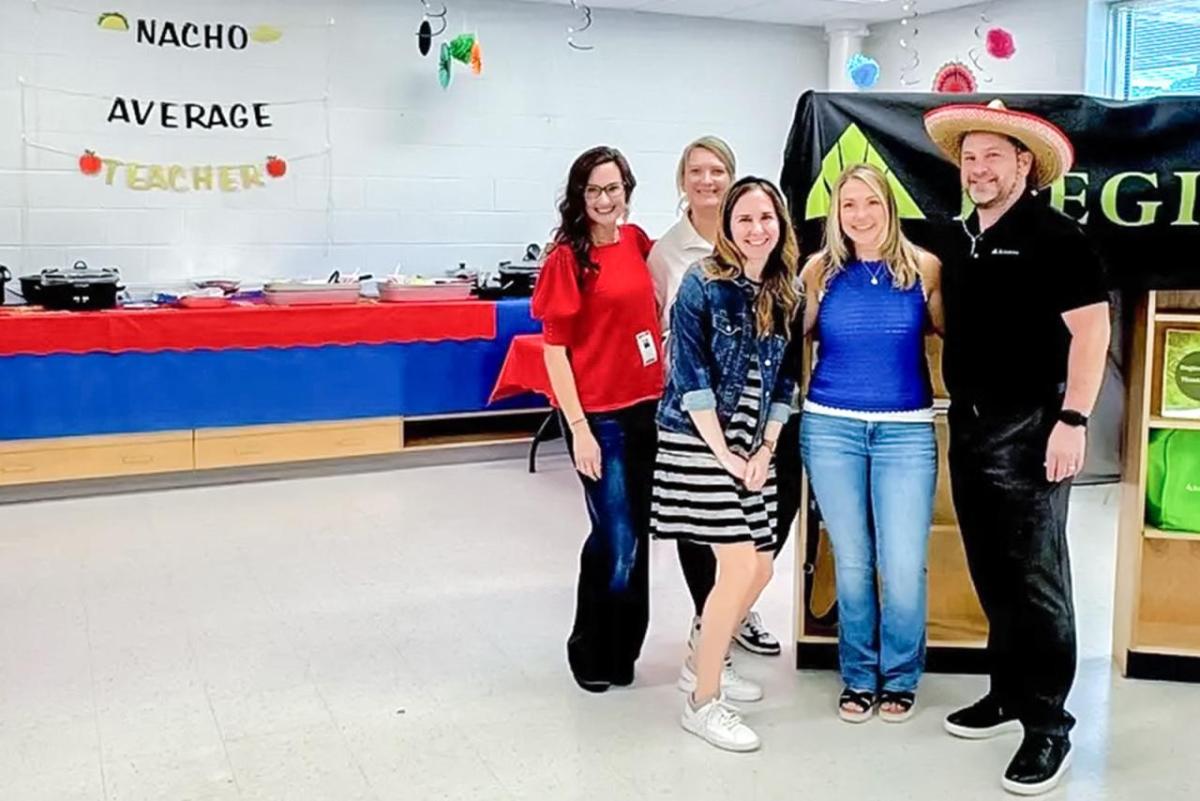 Five people standing together next to sign, "Nacho Average Teacher"